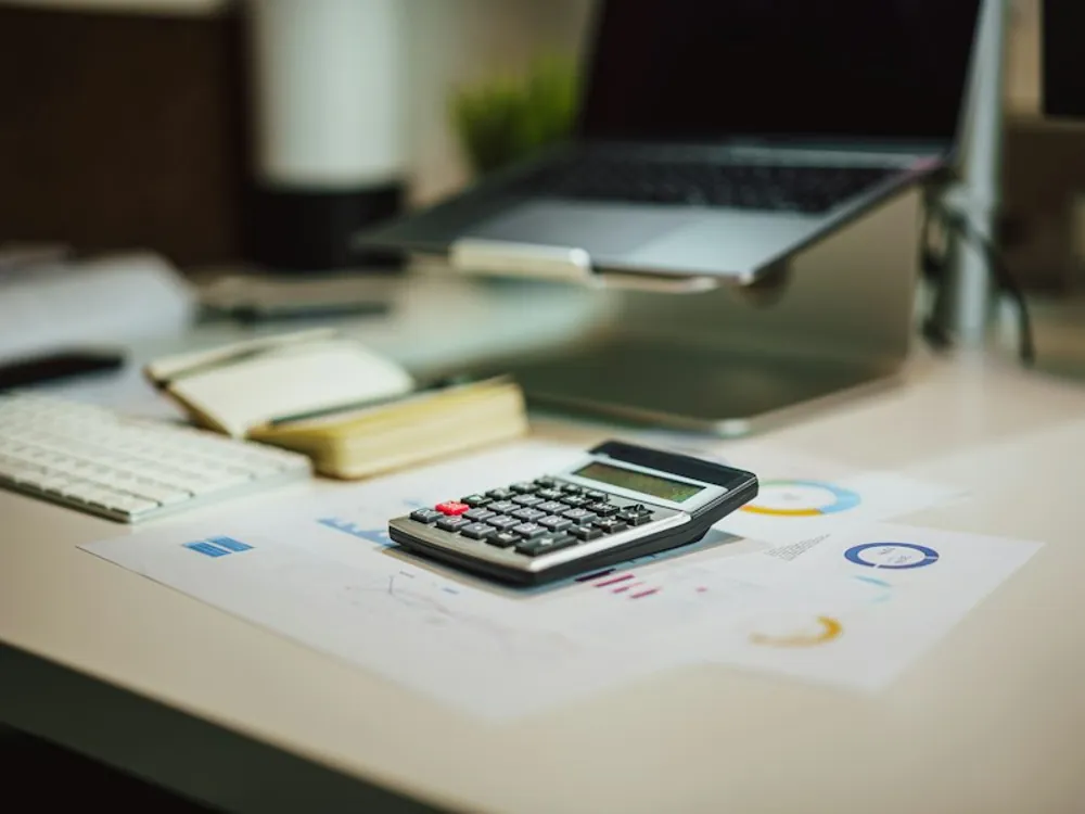 Calculadora e papéis sobre uma mesa de trabalho
