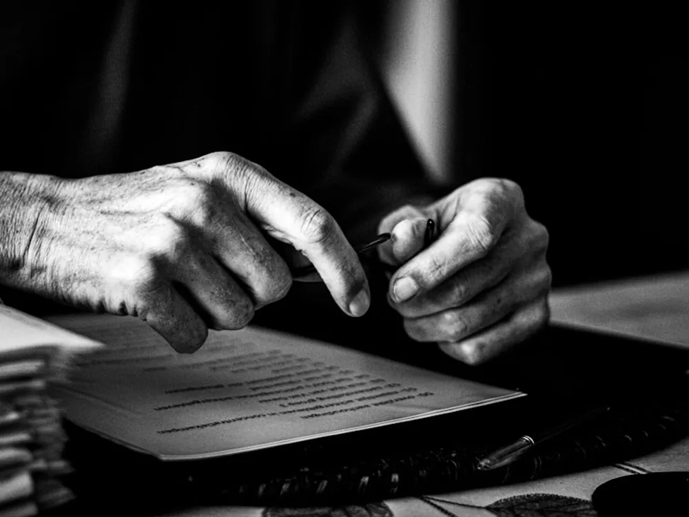 Mãos sobre documentos, em preto e branco